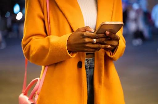 Person in yellow coat using mobile phone